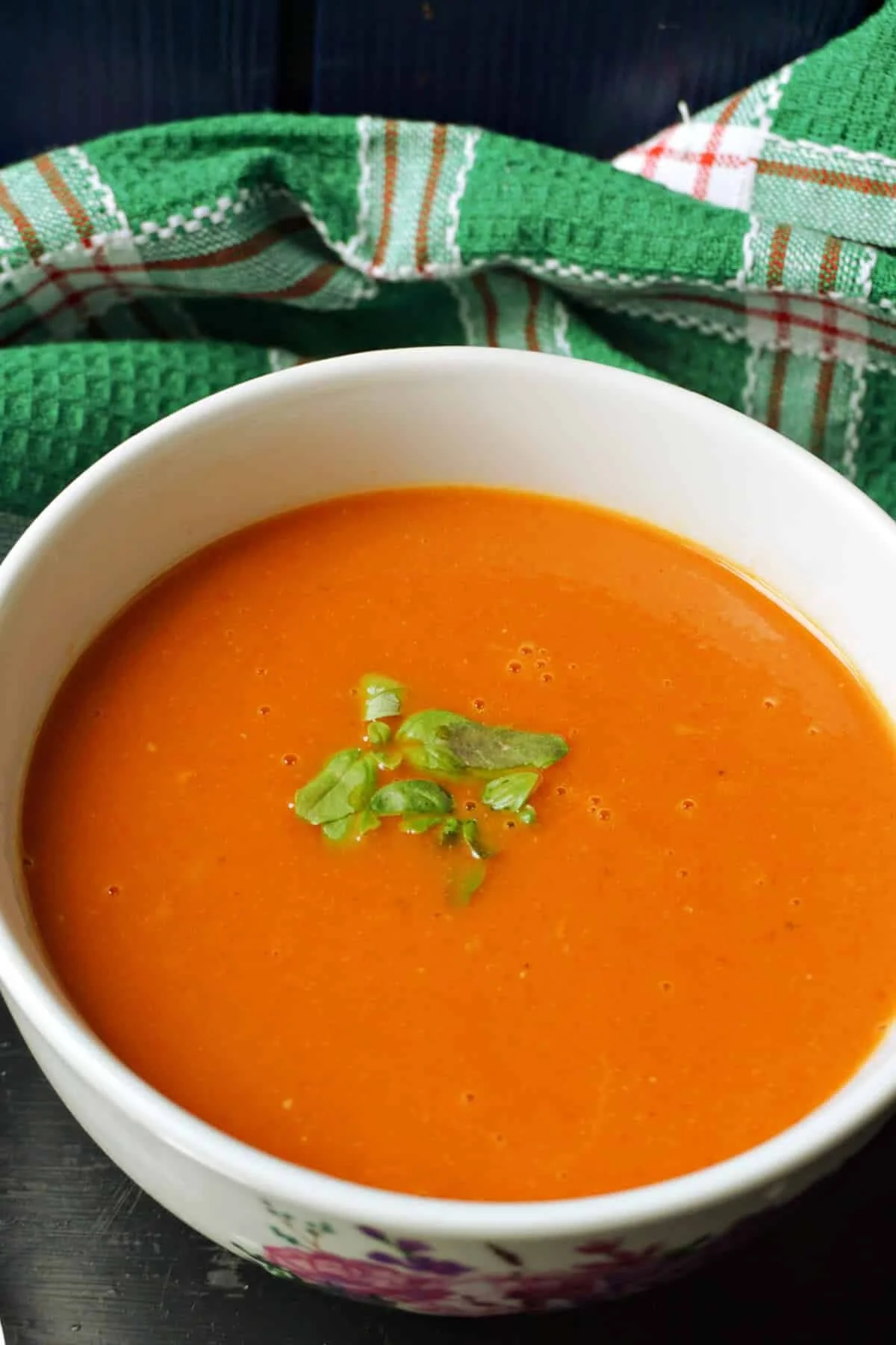 Bowl of easy tomato basil soup made without cream, garnished with fresh basil